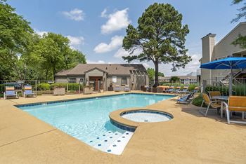 A swimming pool surrounded by trees and chairs.